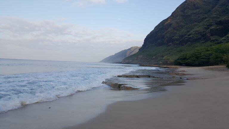 Waianae Coast Beach in Hawaii with the mountains close to the water.