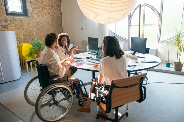 An inclusive and modern office that has a person in a wheelchair and two people sitting beside him