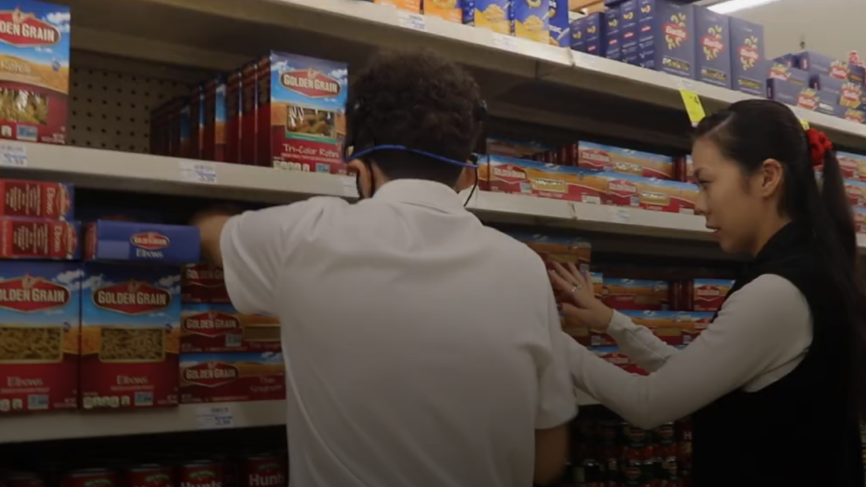 Two individuals are actively stocking shelves in what appears to be a grocery store.